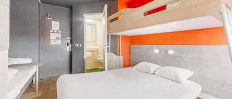 A modern hotel room with a bunk bed, a desk, and a bathroom visible through an open door.