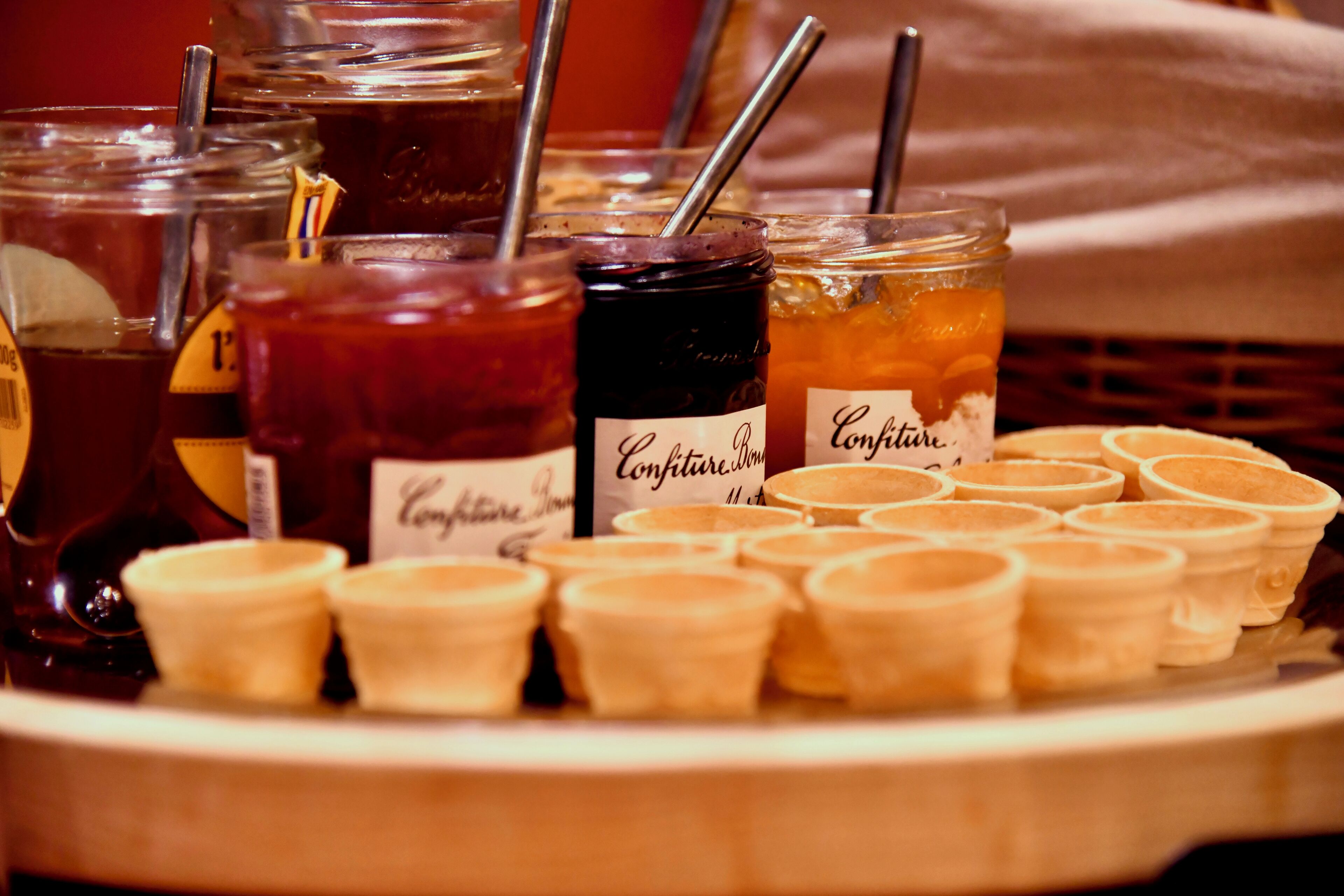 A tray with various jars of jam and a selection of small, round, light-colored containers, possibly for cream or custard.