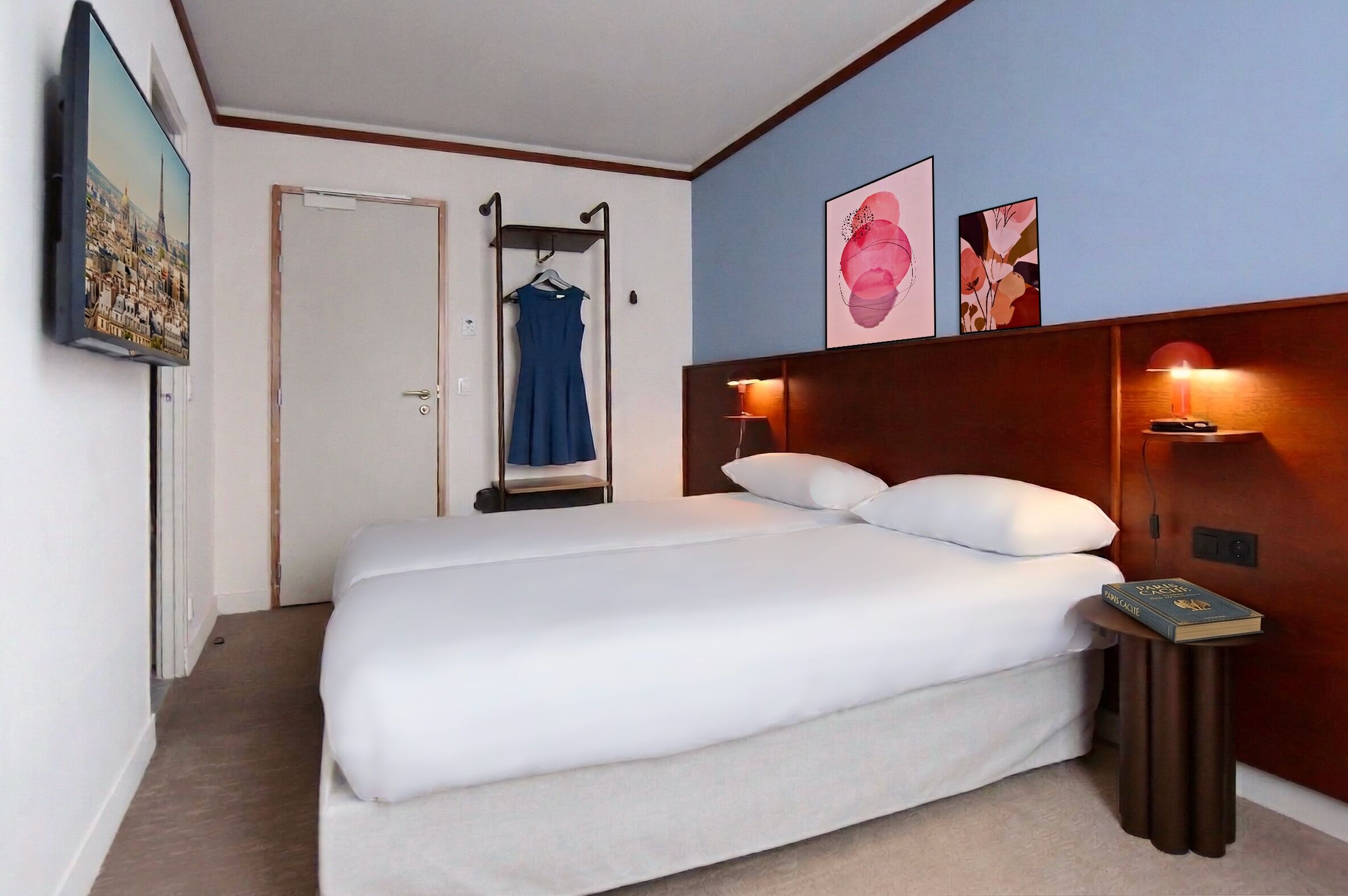Una habitación de hotel con cama, televisor, perchero y obras de arte en la pared.