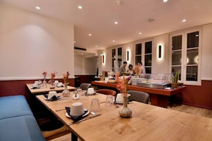 Un comedor de hotel con mesas dispuestas para comidas, un bufé y una zona de estar.