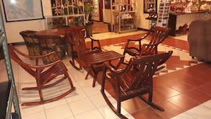Una sala de estar acogedora con muebles de madera, suelo de baldosas y diversos objetos decorativos en estanterías y paredes.