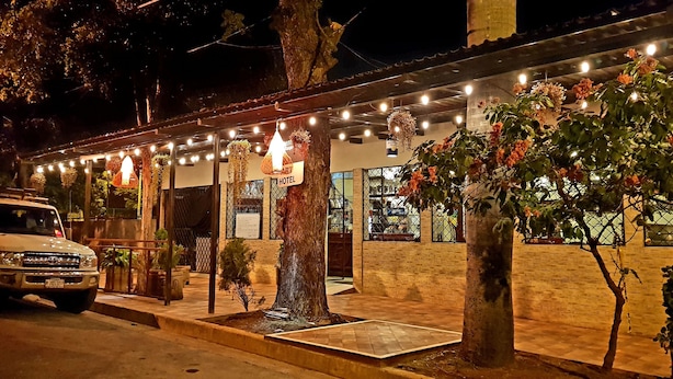 Un hotel con un espacio exterior cubierto, luces colgantes y plantas en macetas.