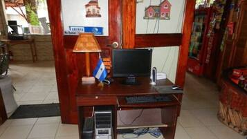 A wooden desk with a computer, keyboard, and a lamp.