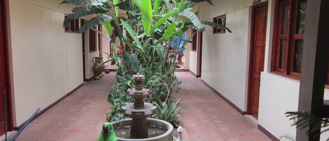 A courtyard with a fountain, a parrot sculpture, and a mushroom sculpture.