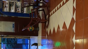 Una habitación con pared de azulejos, una silla de madera, un acuario y una estantería con objetos.