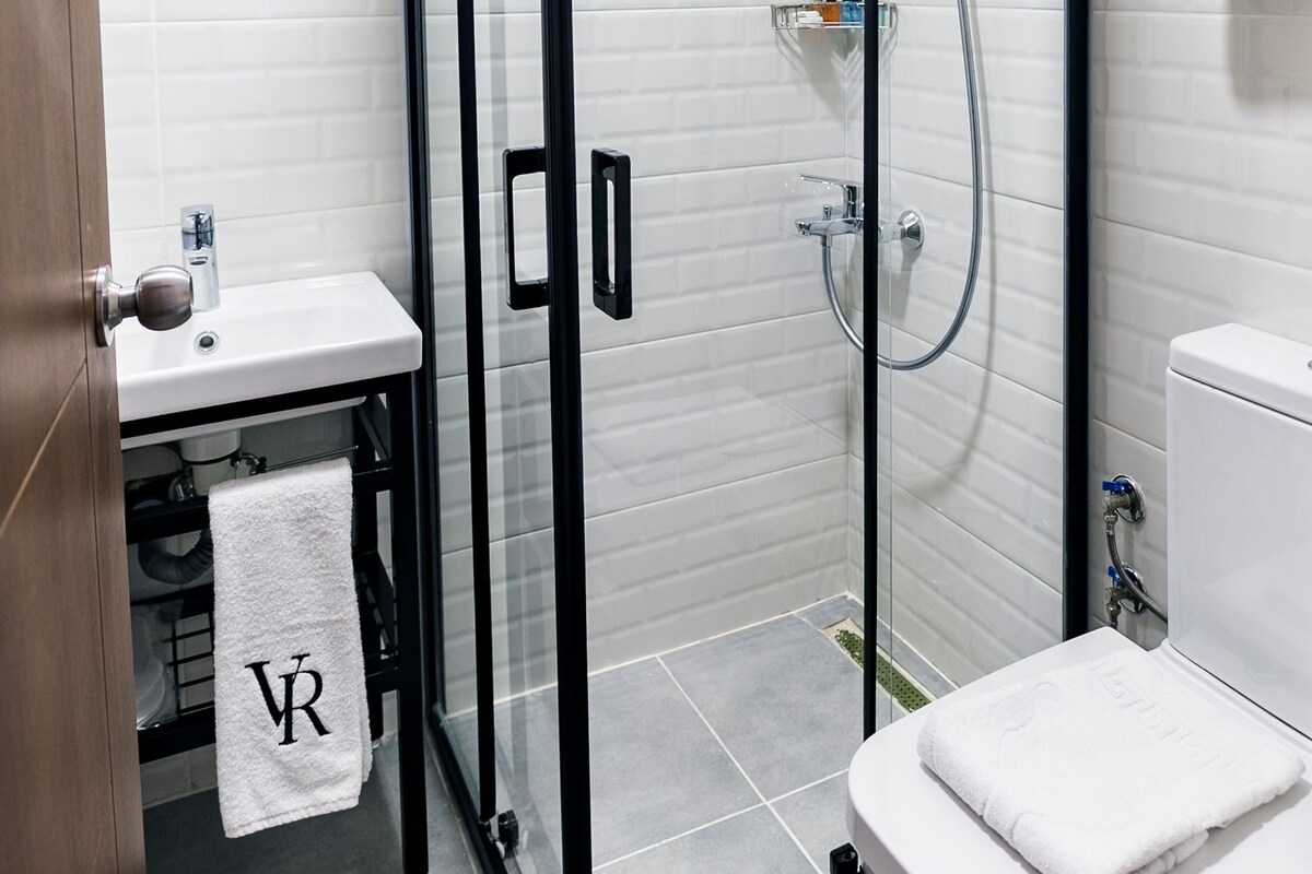 Un baño moderno con ducha envuelta en vidrio, un lavabo blanco y un inodoro.