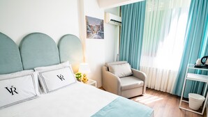 A hotel room with a bed, a chair, a nightstand, a lamp, a radiator, a window with curtains, and a painting on the wall. - Hotel Vera (Istanbul)