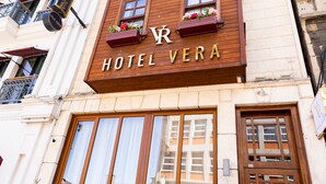 A hotel named "Hotel Vera" with a sign above the entrance, large windows, and a balcony with plants. - Hotel Vera (Istanbul)