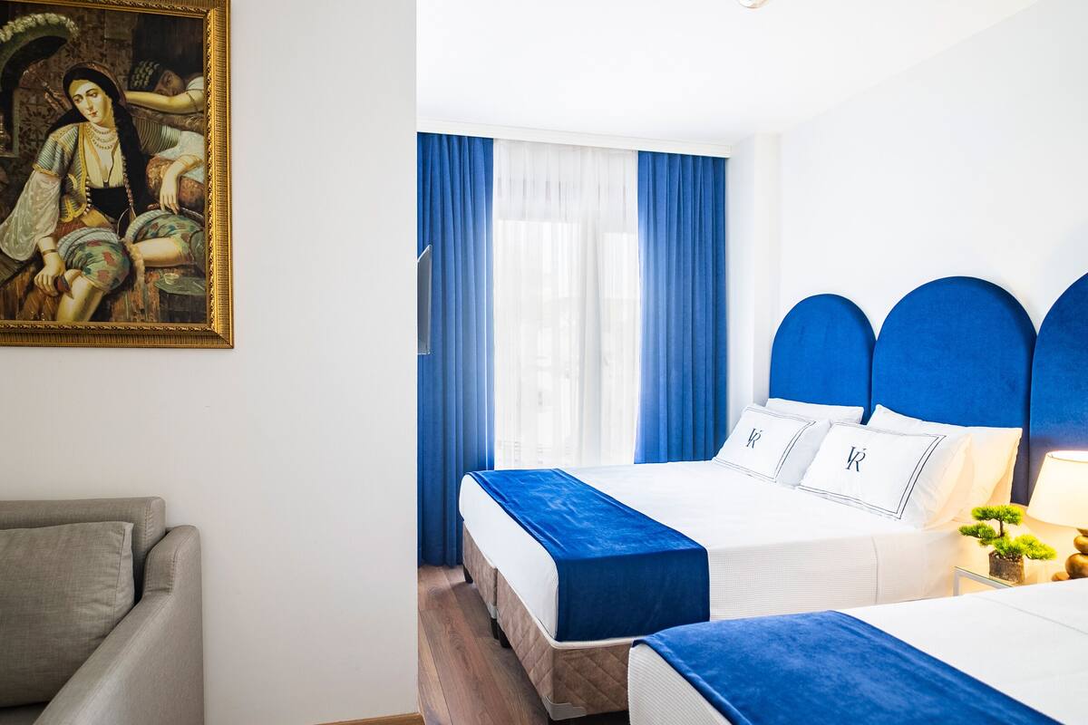 A hotel room with a bed, a chair, and a painting on the wall.