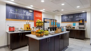 A breakfast bar with a variety of fruits, a waffle station, and a bakery section. - Hampton Inn Milford (Milford)