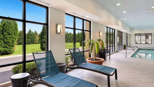 A poolside area with lounge chairs, a potted plant, and a view of the pool. - Hampton Inn Milford (Milford)