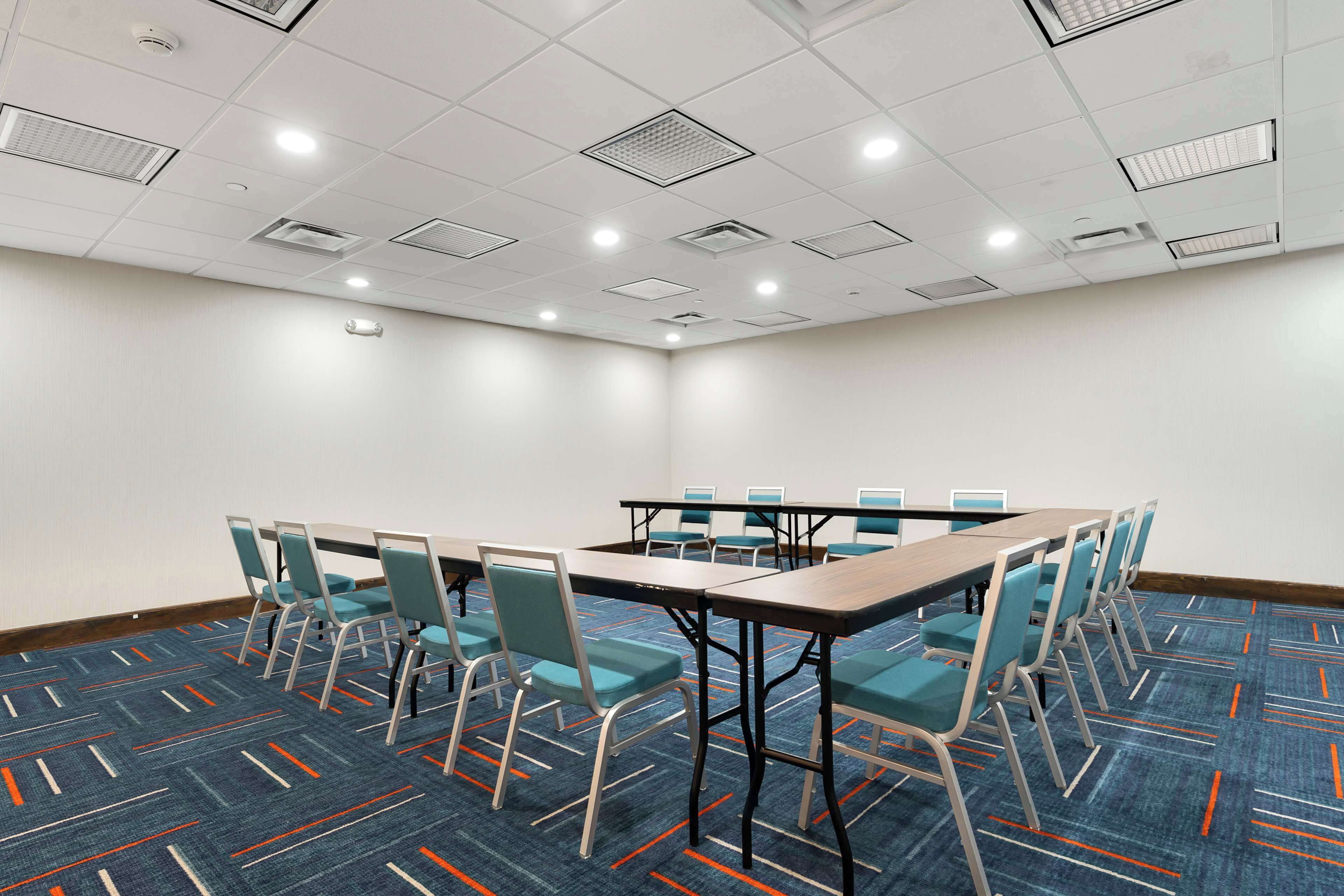 Un salón de conferencias con una larga mesa, sillas y piso alfombrado.