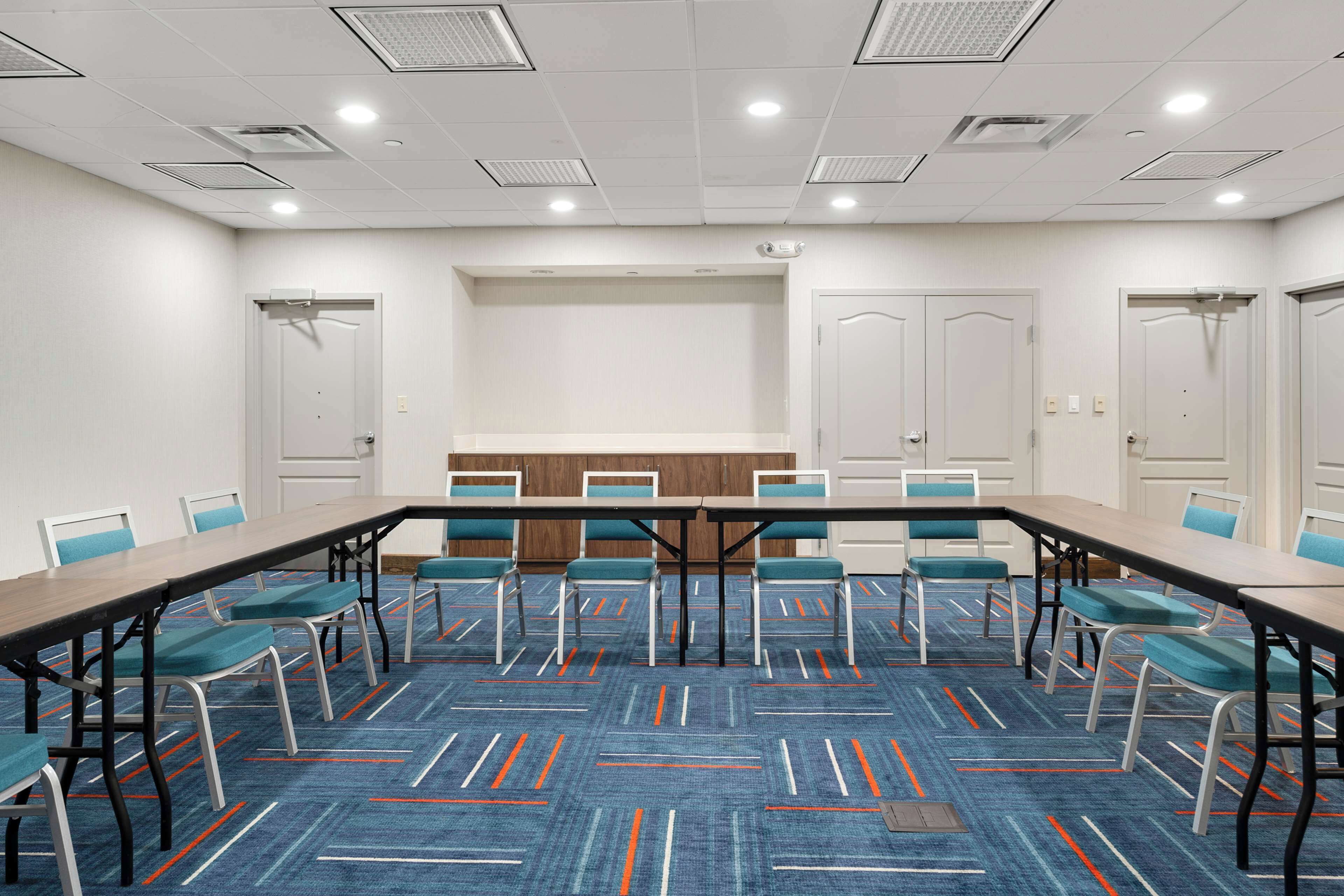 Un salón de conferencias con una larga mesa, sillas y piso alfombrado.