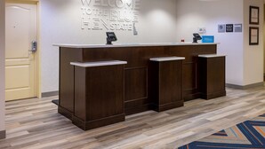 A reception desk with a "Welcome to the Blue Hen State" sign, a phone, and a "Hilton" sign. - Hampton Inn Milford (Milford)