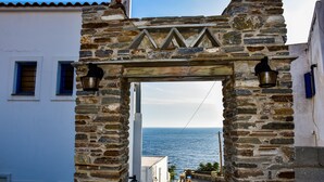 A stone archway with a view of the sea. - Anemos Studios (Andros)