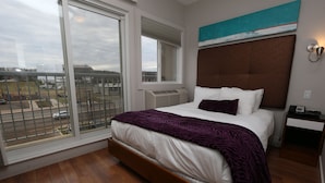Een moderne hotelkamer met een groot bed, uitzicht op de stad en een balkon.