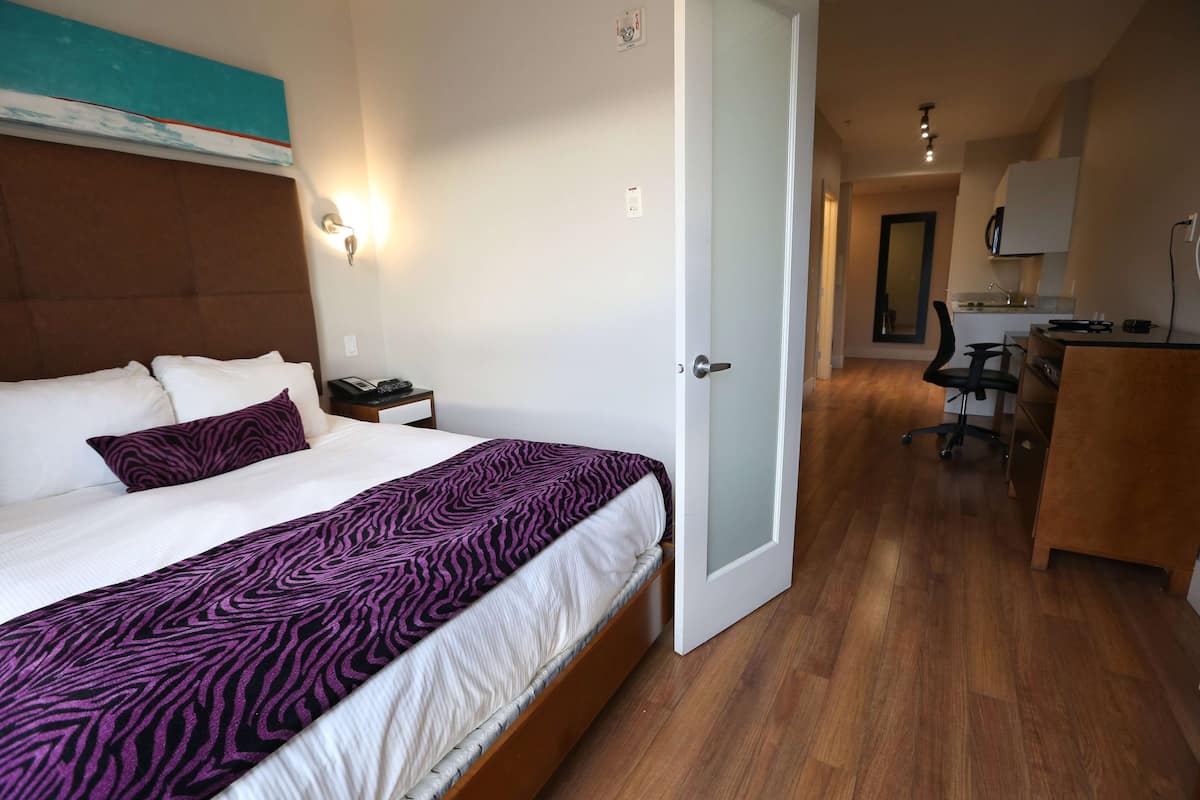 Una habitación de hotel con cama, mesita de noche y escritorio con silla.