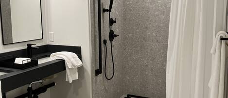 Un baño moderno con ducha, lavabo y espejo.