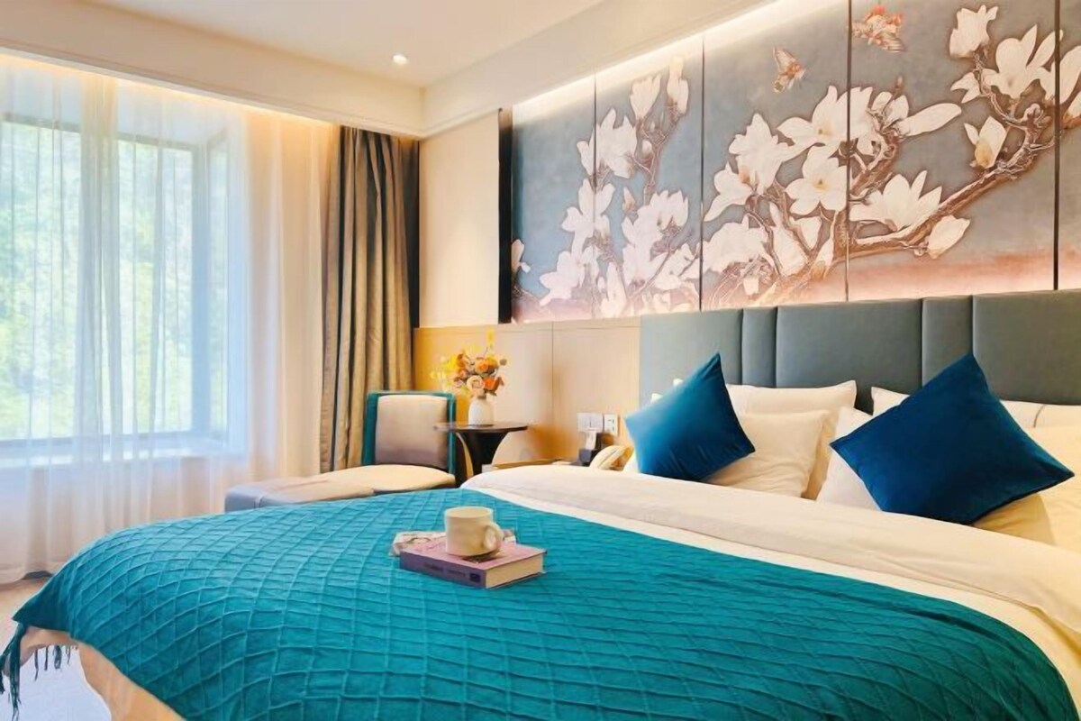A hotel room with a large bed, a nightstand, and a wall-mounted artwork.