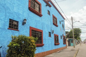 A blue building with red window frames and barred windows. - Hotel La Casona Real (Cozumel)