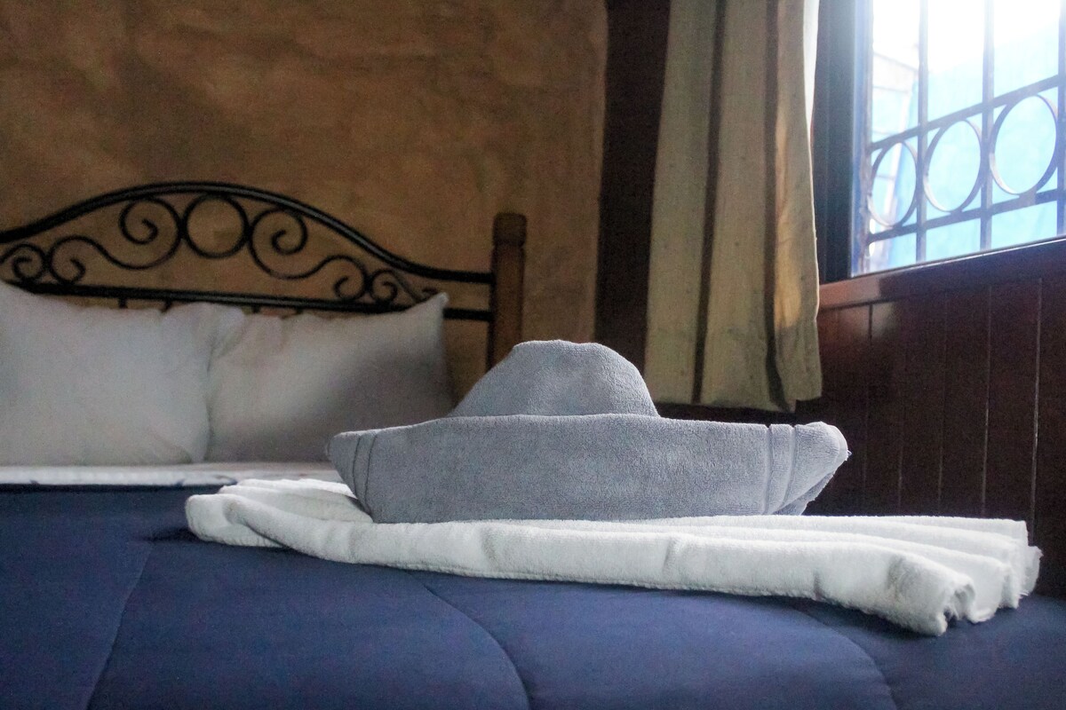 A bed with a dark blue bedspread and a white pillow.