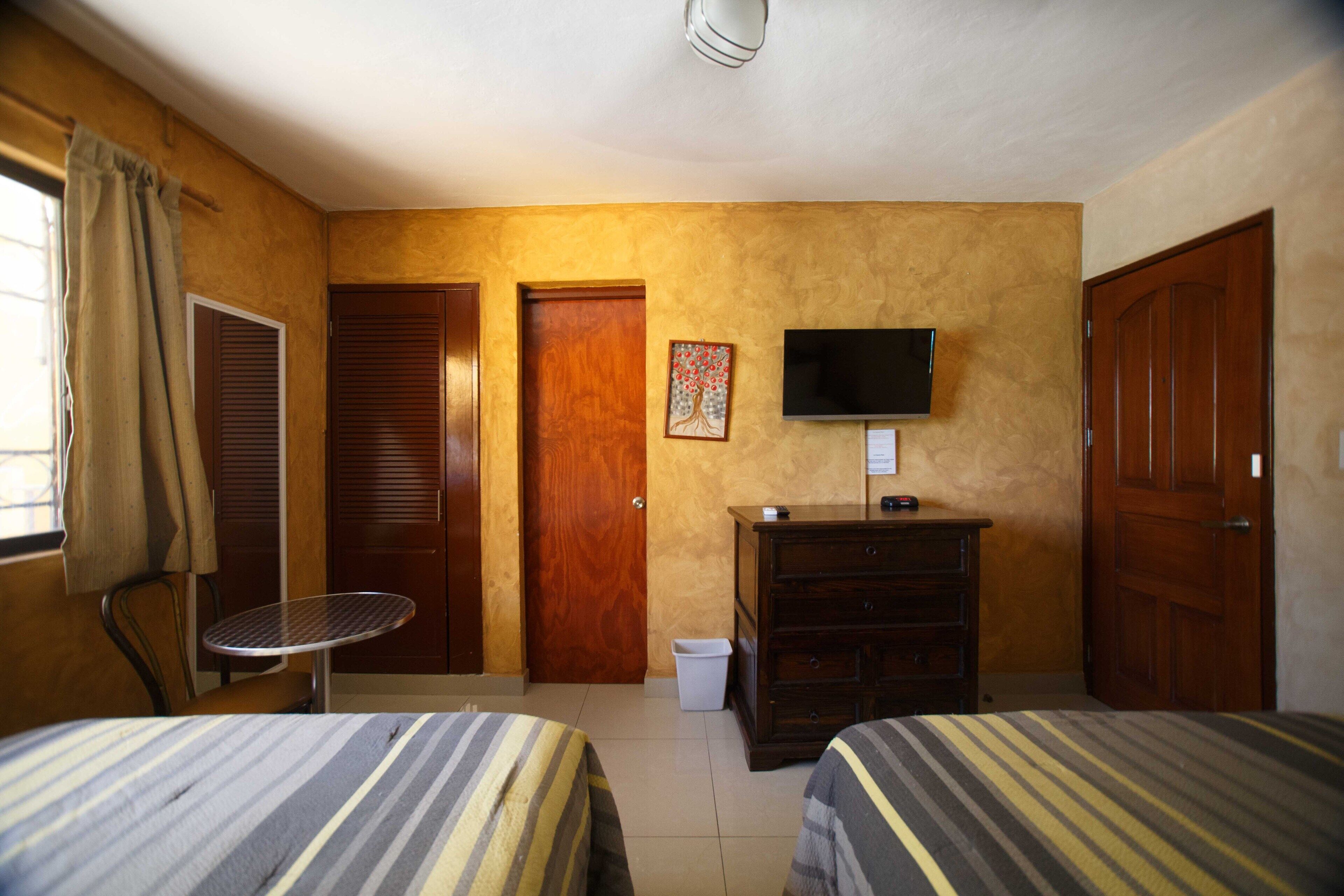 Habitación de hotel con dos camas, televisor, escritorio y una silla.