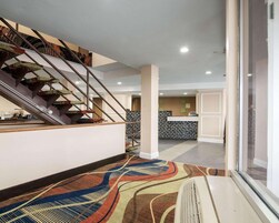Un moderno vestíbulo de hotel con una escalera, una recepción y una alfombra estampada.