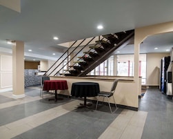 Un espacio interior amplio con una escalera central, dos mesas redondas con sillas y una cocina al fondo.