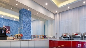 A modern kitchen with a blue mosaic backsplash, a central column, and a red countertop. - Jinjiang Inn Shenzhen Airport (Shenzhen)