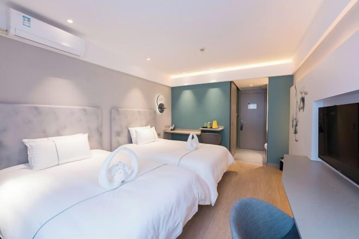 Een hotelkamer met twee bedden, een televisie en een badkamer zichtbaar door een geopende deur.
