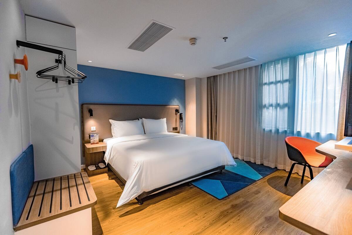 Ein modernes Hotelzimmer mit einem großen Bett, einem Schreibtisch und einem Stuhl.