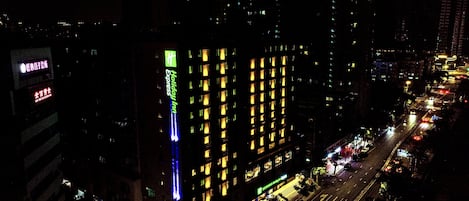 Un immeuble de grande hauteur, avec des fenêtres illuminées et une enseigne indiquant la présence d’un hôtel Holiday Inn Express.
