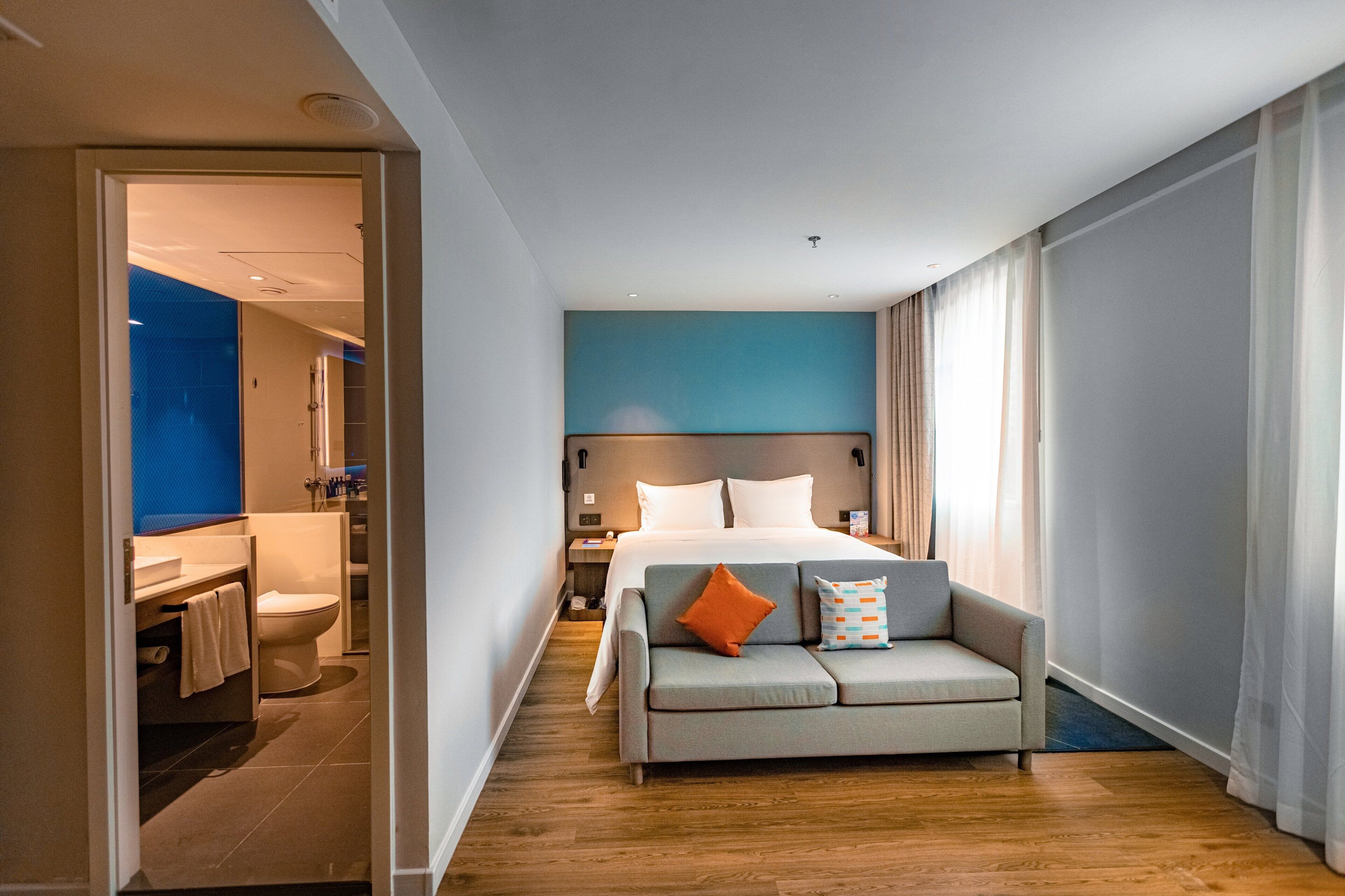 A hotel room with a bed, a sofa, a desk, and a bathroom.