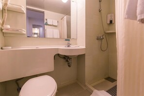 Un baño con lavamanos blanco, espejo e inodoro. Hay una zona de ducha con cortina y un cabezal de ducha de mano.