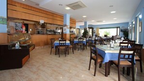 A restaurant with a counter, tables, and chairs. - Hotel Oasis (Conil de la Frontera)