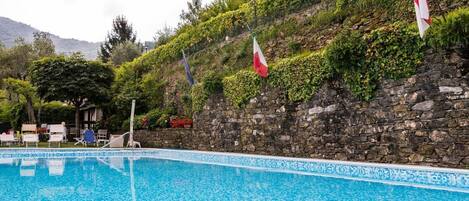 En säsongsöppen utomhuspool, parasoller och solstolar