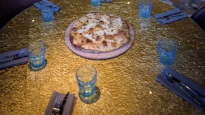 A restaurant with a table set for two, featuring a pizza and blue glasses. - Manuelina Taste Hotel (Recco)