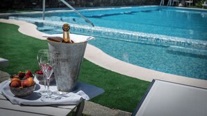 A poolside setting with a champagne bucket, glasses, and fruit on a table. - Manuelina Taste Hotel (Recco)