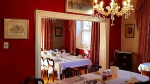 Ein Esszimmer mit einem großen Spiegel, roten Wänden und einer Kristallleuchter.