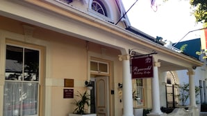 Ein Gebäude mit hellbeiger Fassade, einem Schild mit der Aufschrift "Ryneveld Country Lodge" und einem befestigten Eingang.