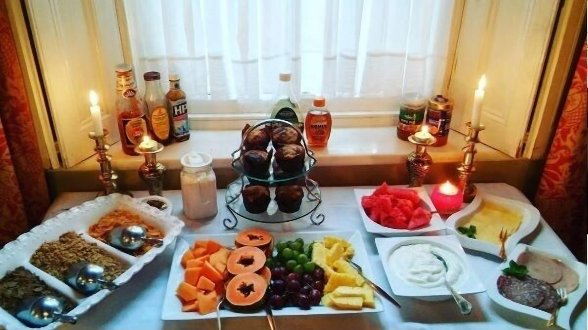 A table with various food items and condiments, candles, and bottles of beverages.
