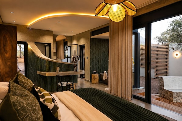 A modern bedroom with a curved staircase, a large bed, and a view of the outdoors. - Tshukudu Game Lodge (Hoedspruit)