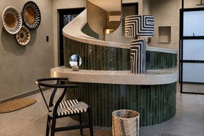 A modern reception area with a curved counter, a chair, and decorative wall art. - Tshukudu Game Lodge (Hoedspruit)