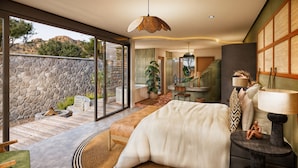 Un dormitorio moderno con una cama grande, una sala de estar, un baño y vistas al exterior.