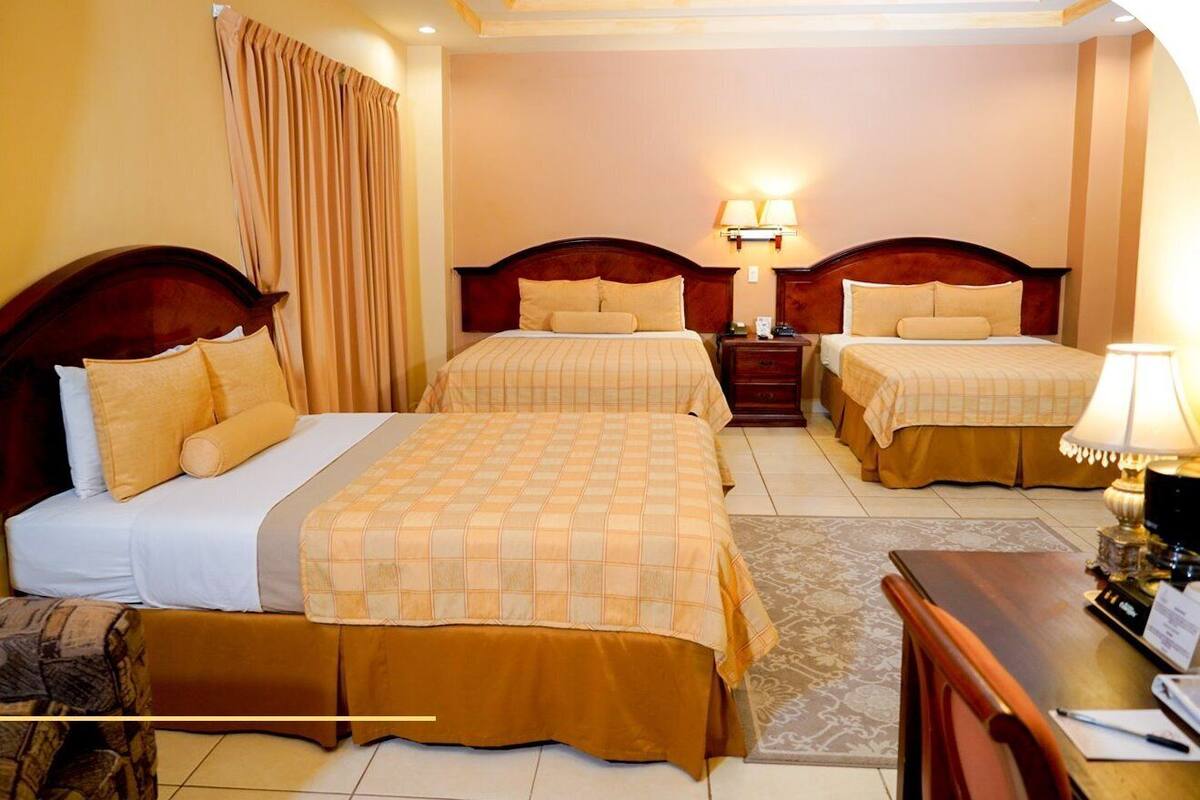 Ein Hotelzimmer mit zwei Betten, einem Schreibtisch und einem Nachttisch.