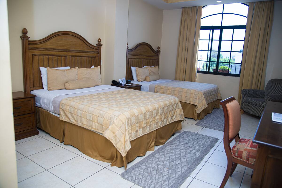 Ein Hotelzimmer mit zwei Betten, einem Schreibtisch und einem Stuhl.