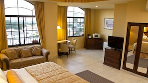 A hotel room with a bed, a sofa, a desk with a chair, a television, and a dresser. - Monteolivos (San Pedro Sula)