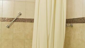 A bathroom with a bathtub, a shower curtain, and a window.