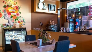 A cafe interior with a wooden table, chairs, a coffee machine, and a display case with pastries. - Monteolivos (San Pedro Sula)