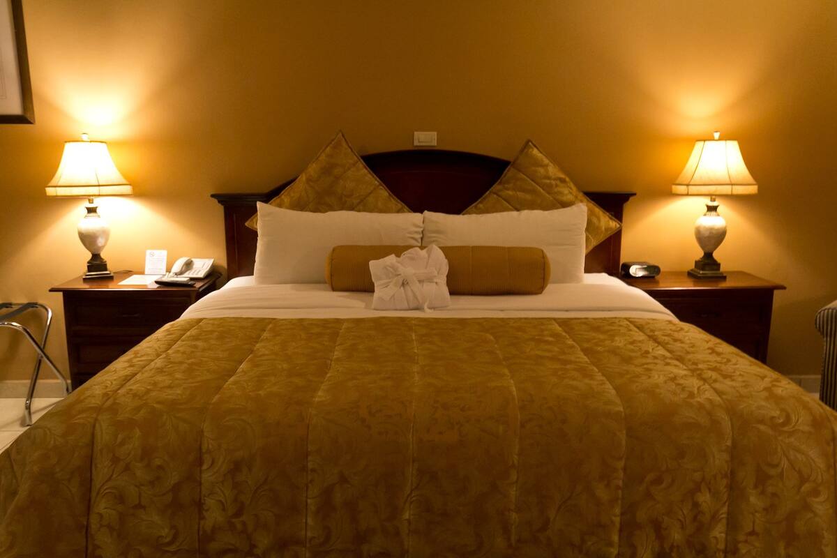 Ein Hotelzimmer mit einem großen Bett, zwei Nachttischen mit Lampen, einem Telefon und einem Bademantel auf dem Bett.